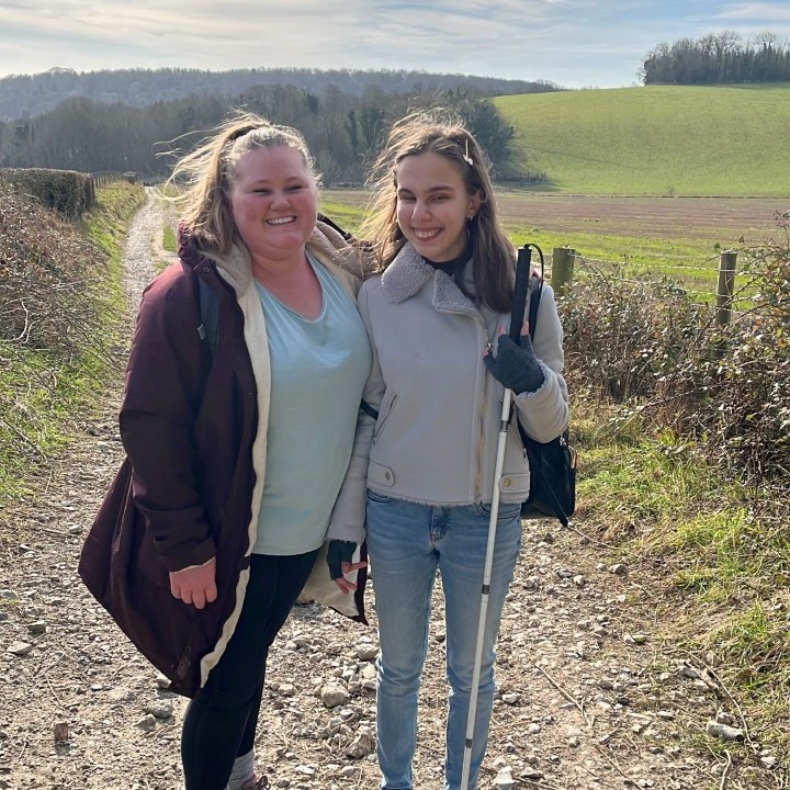 photograph of two people walking in the countryside using a mobility cane