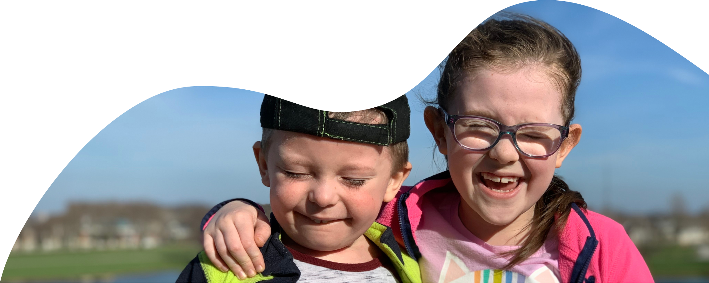 Two young children, both smiling with their arms around each other